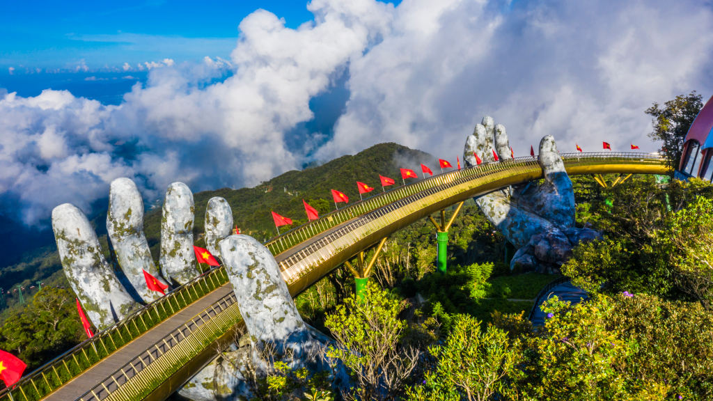 Aerial view of the Golden Bridge is lifted by two giant hands and two rows of Vietnamese flags on Ba Na Hill in Danang, Vietnam.